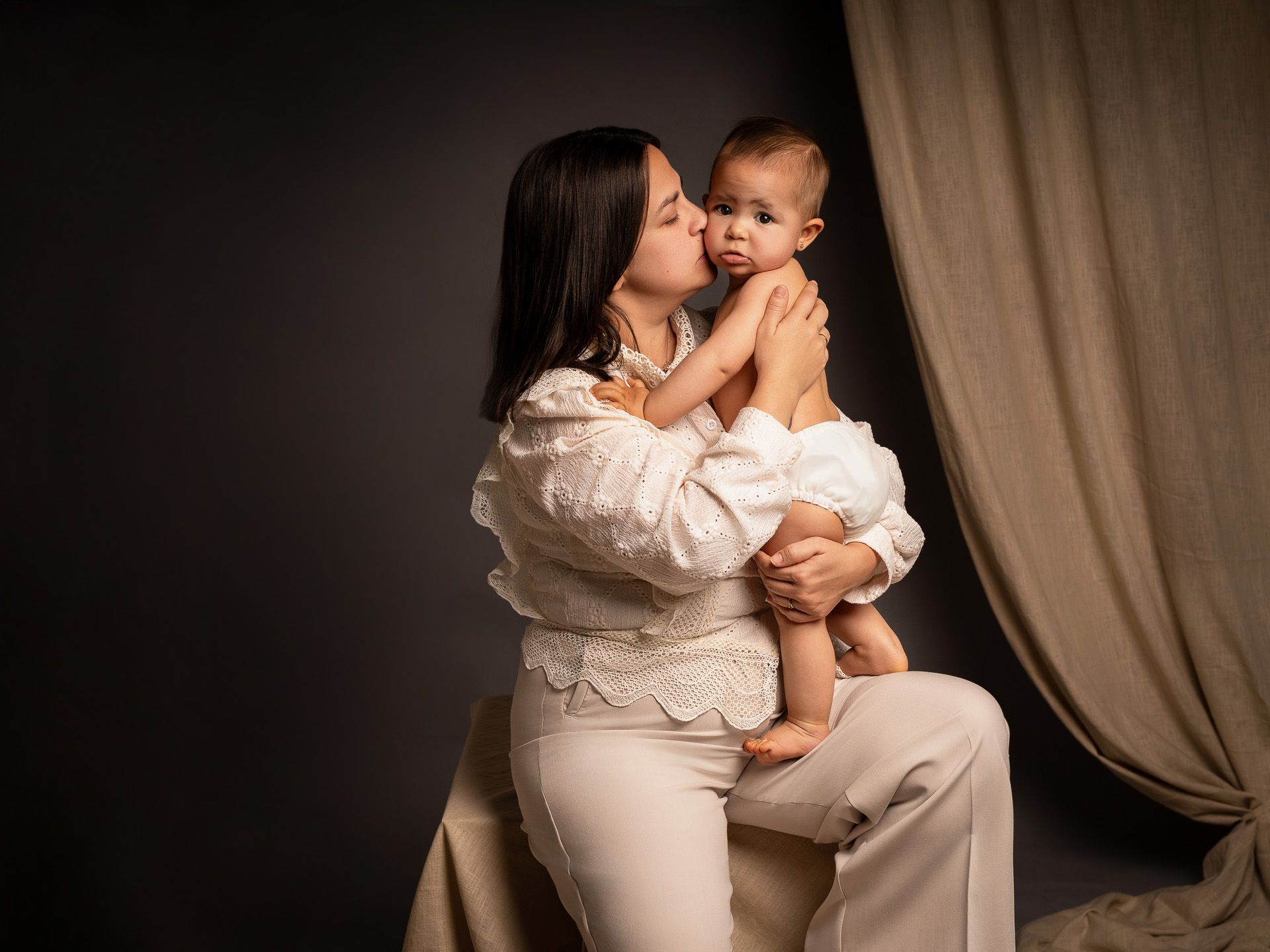 Beso lleno de amor de mamá a su bebé, capturado en una sesión íntima del Día de la Madre.