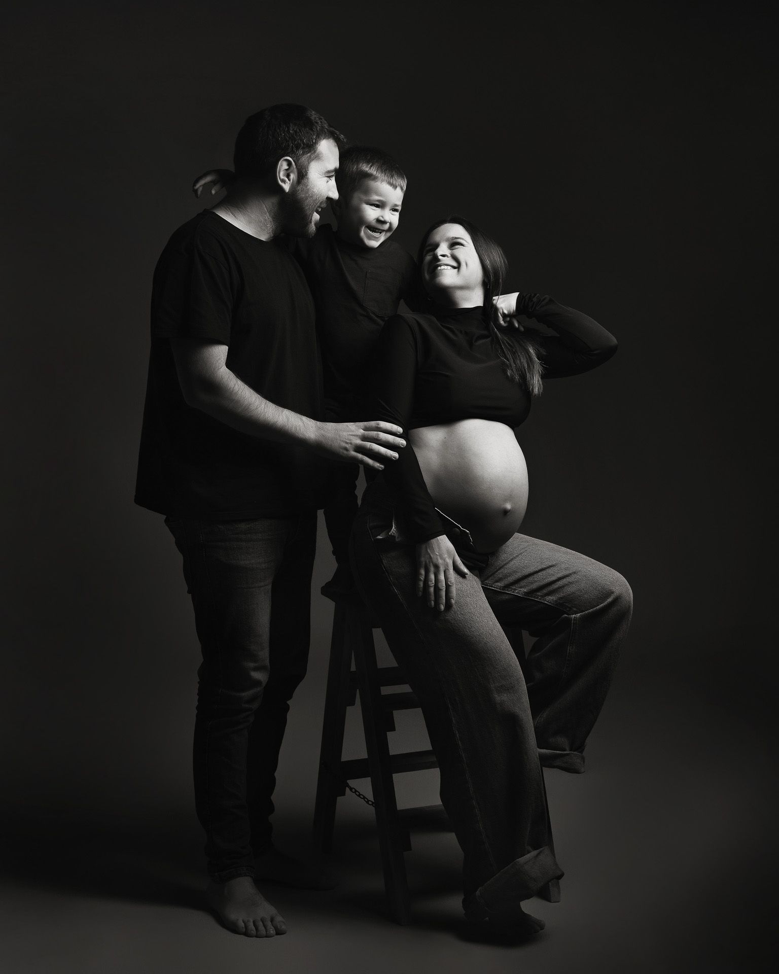 Retrato familiar en blanco y negro con niño sonriente en sesión de embarazo