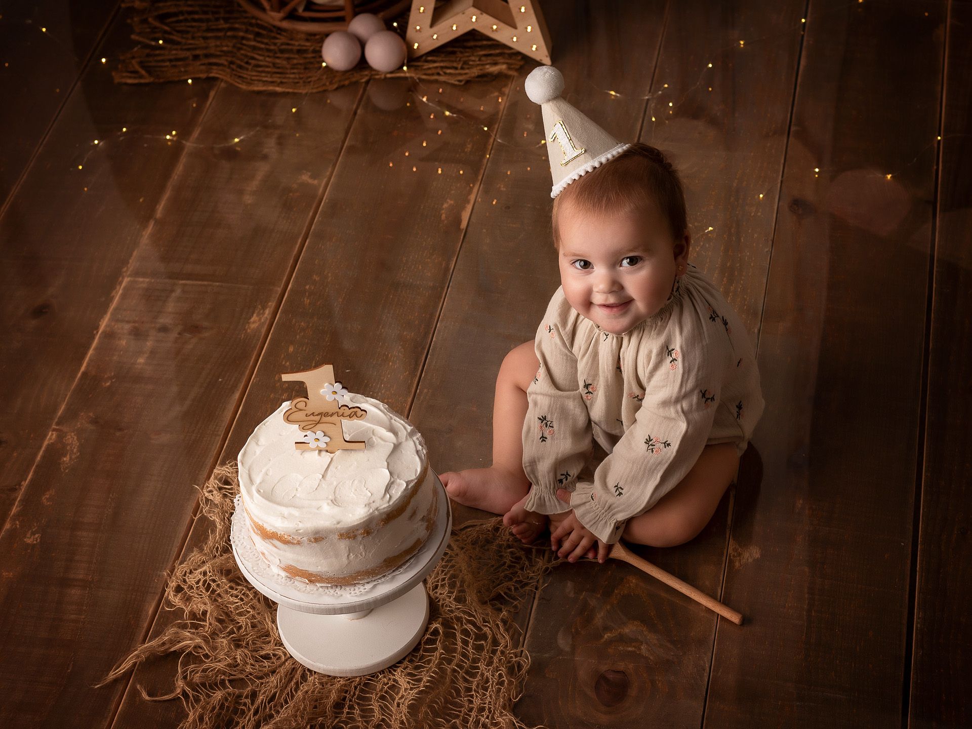 Eugenia sonriendo junto a su tarta personalizada en su primer cumpleaños.