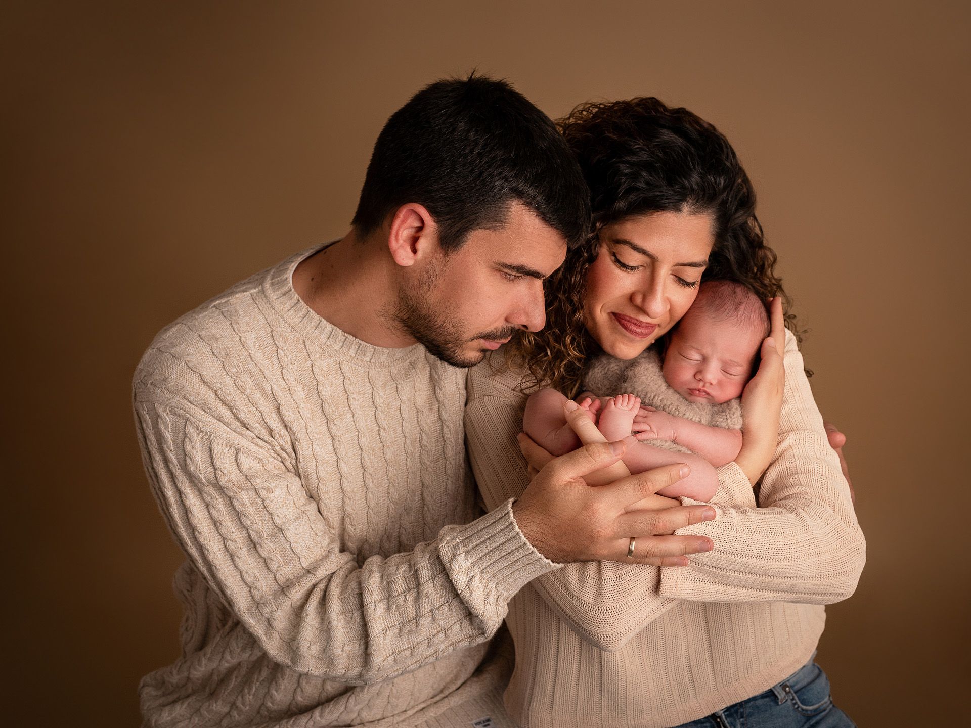 Papás emocionados abrazando a su bebé recién nacido en retrato íntimo