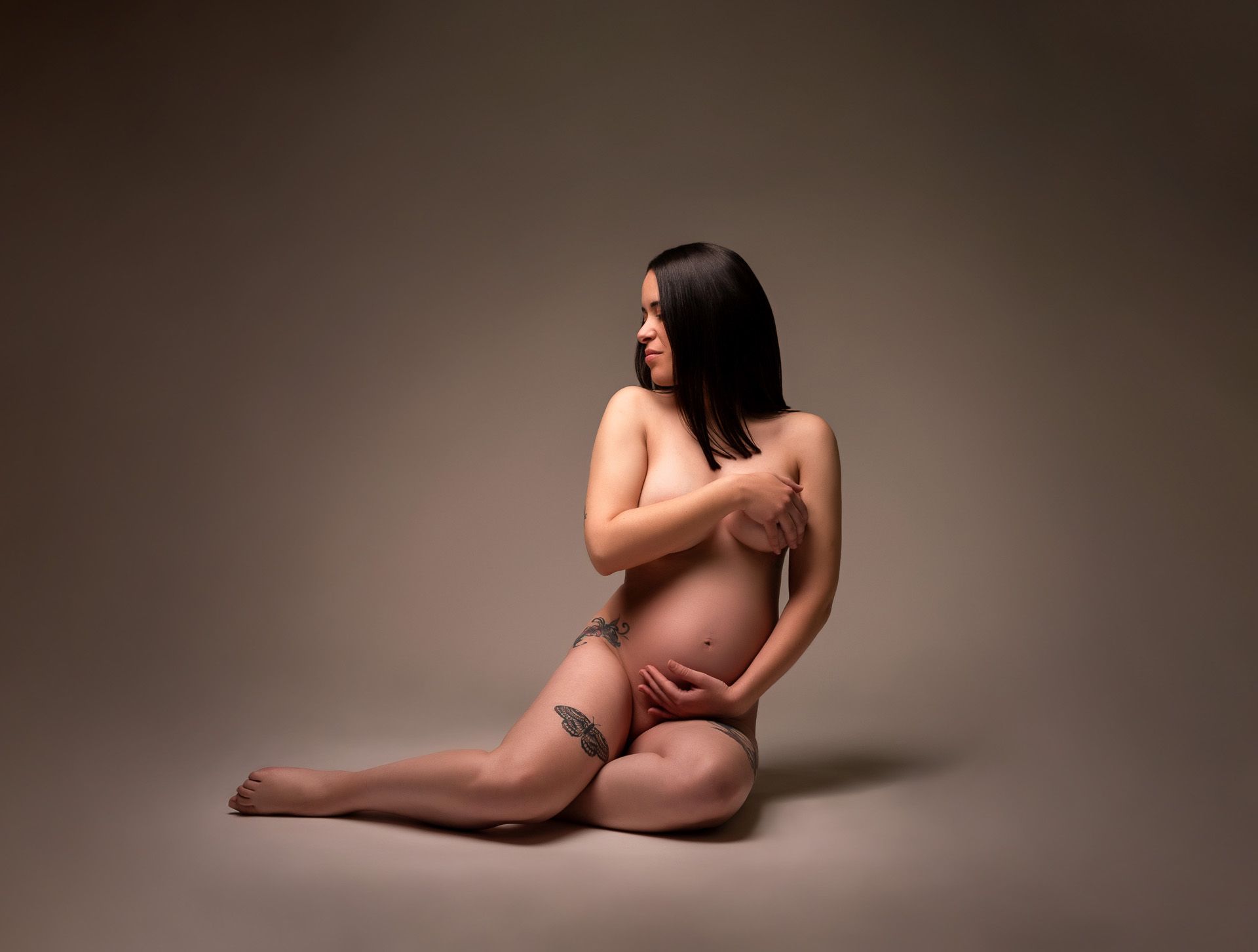 Mujer embarazada posando desnuda de forma artística, con tatuajes visibles
