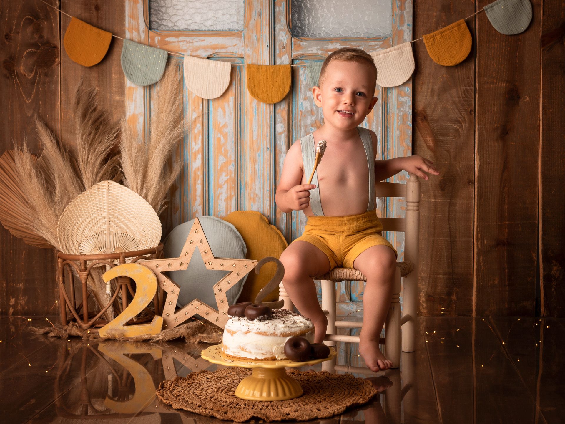 Niño de dos años posando con pastel decorado en sesión de segundo cumpleaños.
