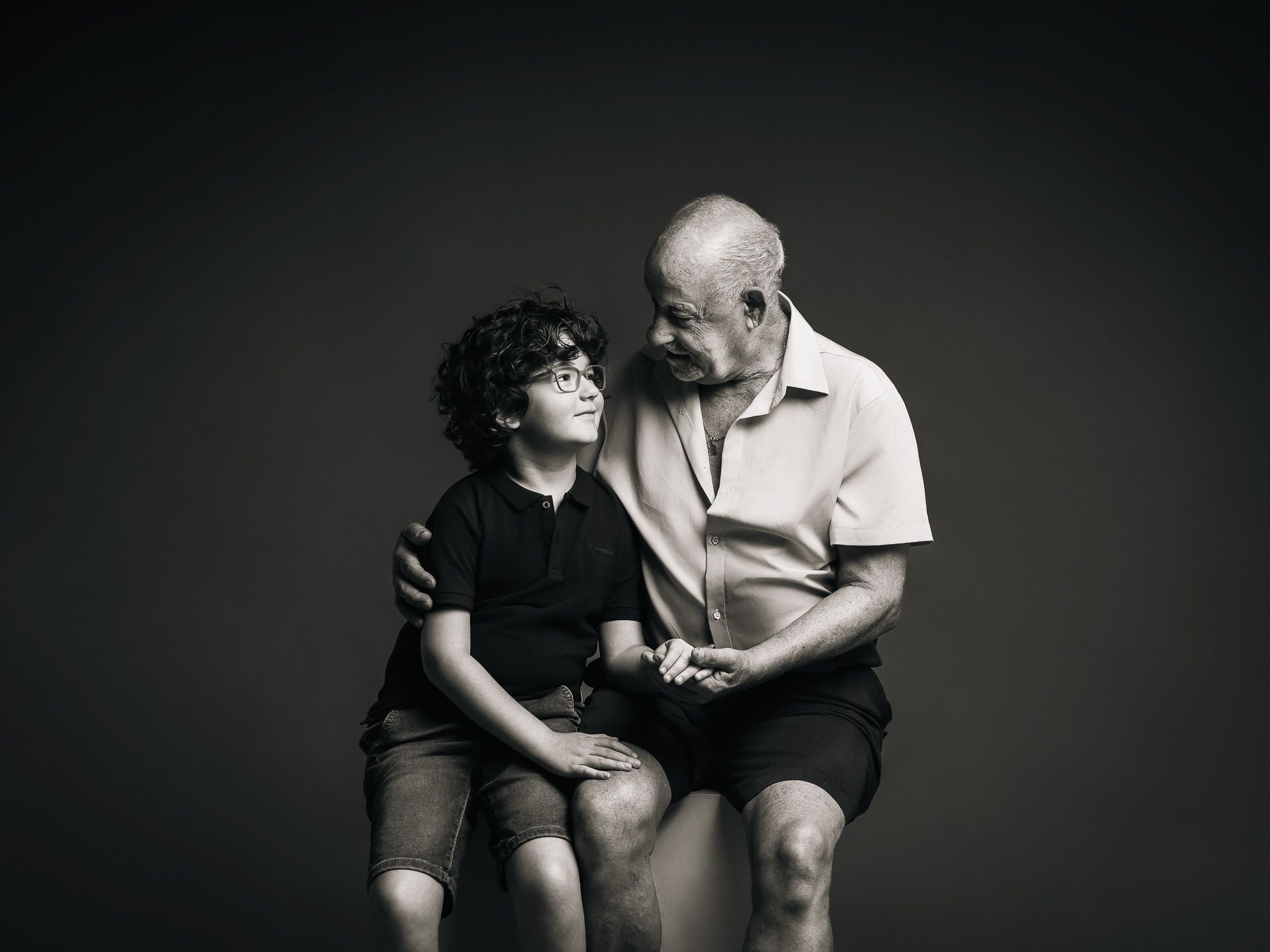 Abuelo besando a su nieto mientras lo abraza con ternura durante una sesión de fotografía emocional en Mérida.