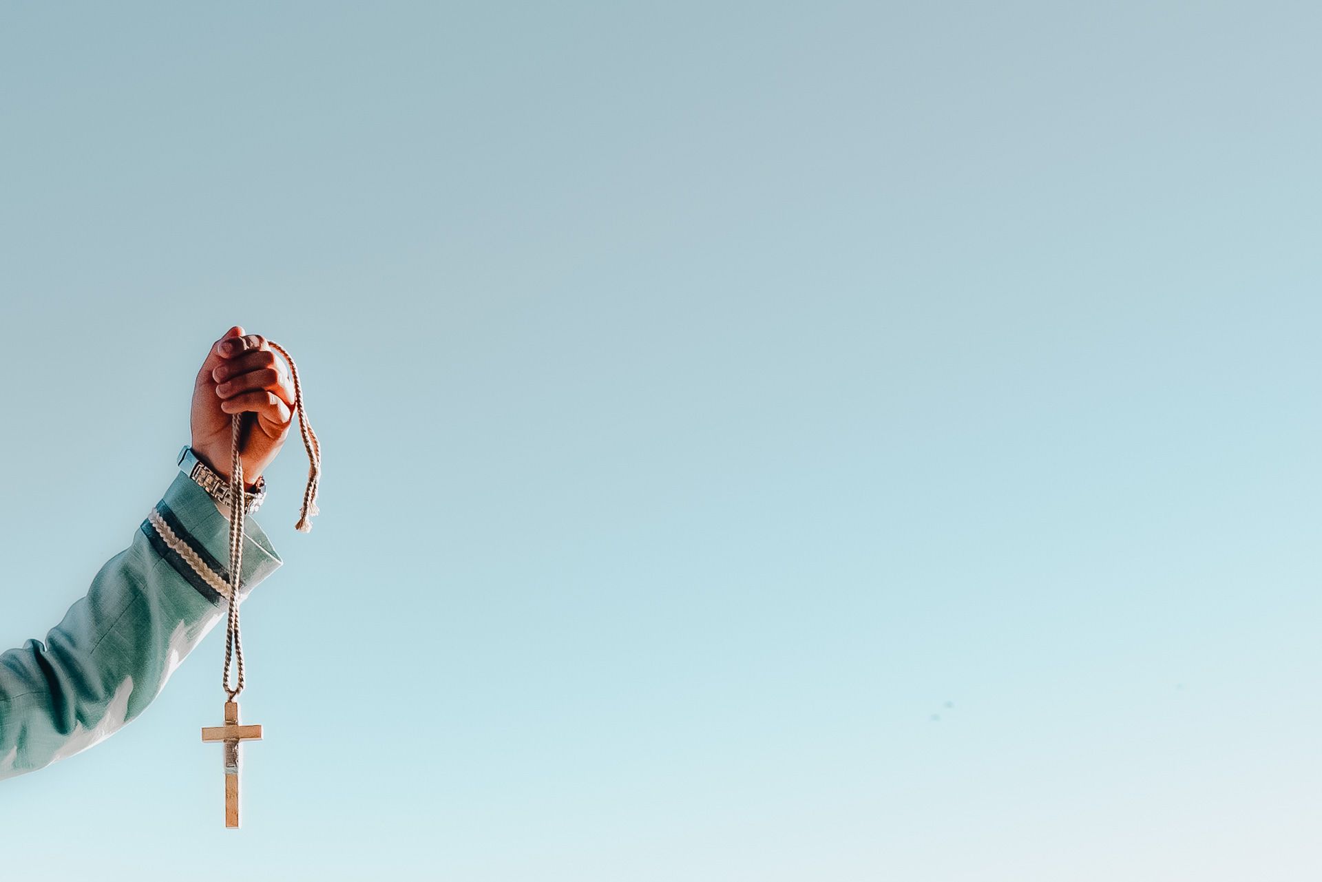 Detalle de la mano de un niño sosteniendo la cruz de su primera comunión, fotografía artística