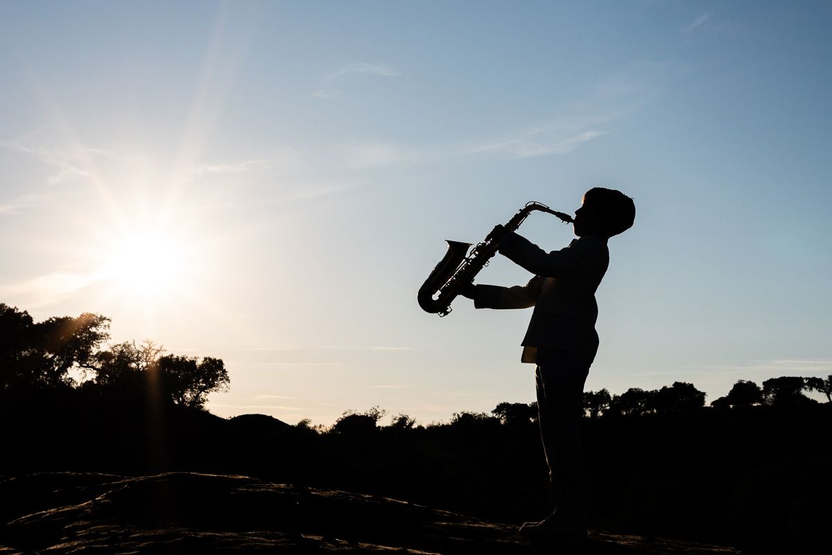 Silueta de niño con saxofón al atardecer en sesión de Comunión